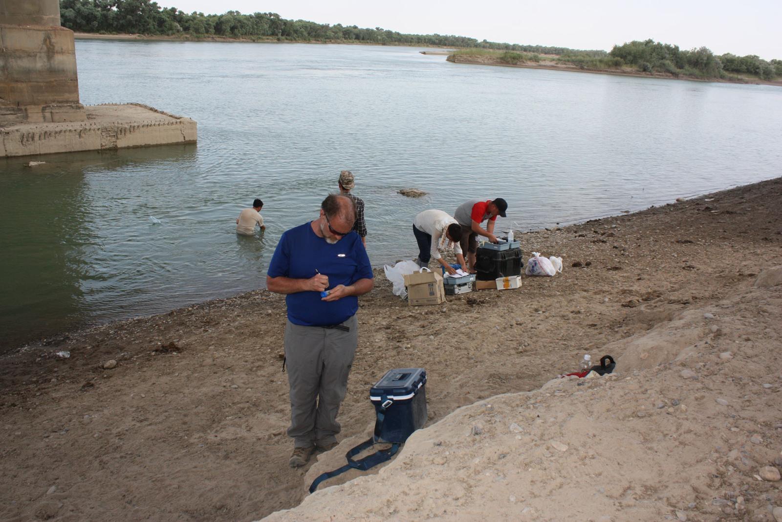 People working on edge of water taking measurements